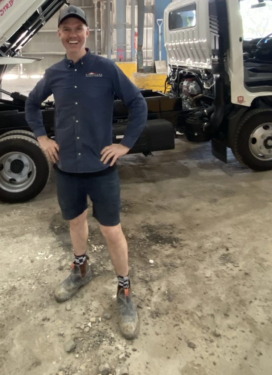 A Trash Talk crew member standing in front of the tipper truck